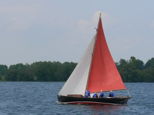 After thousands of volunteer hours by the Marine Museums restoration boat building crew, the “Mowat” boat sets sail in Kingston Harbour. She is named after her last owner, the late Angus Mowat (father of Farley) who rescued the boat and then re-rigged her as a sloop. The restoration was preceded by extensive research. Her symmetrical lines are just visible.